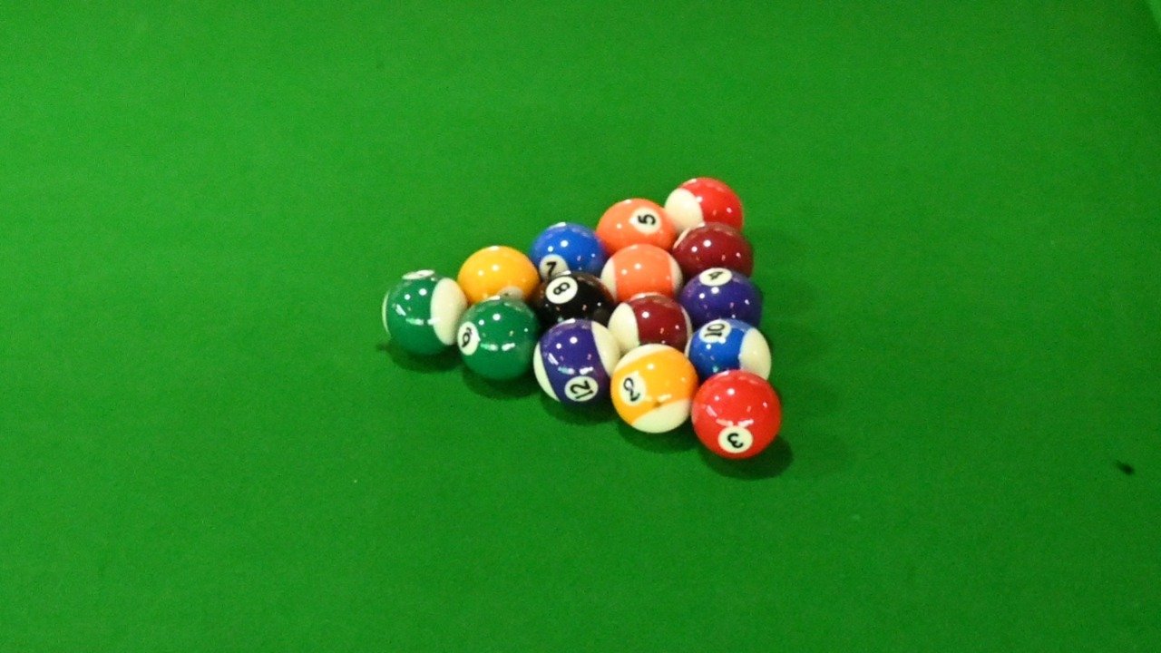 Numbered pool balls arranged in a triangle on green table cloth