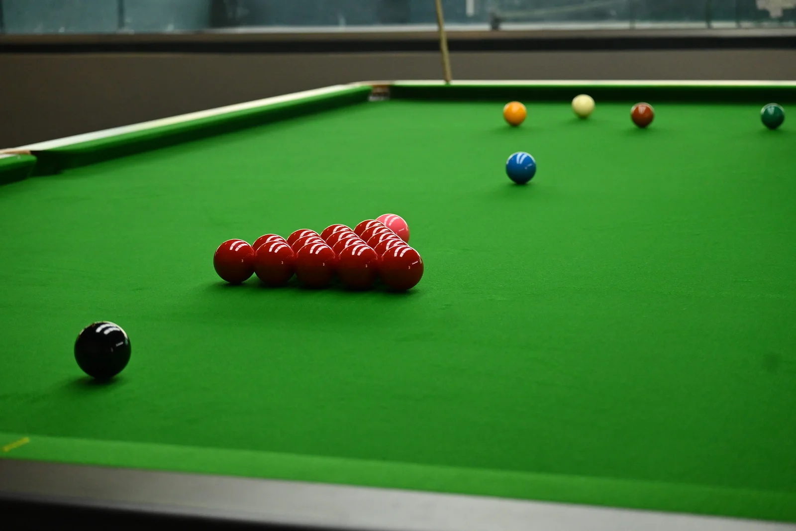 Snooker table with a triangle of red balls and coloured balls on green cloth